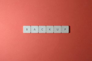Free Close-up of keyboard keys spelling 'BACKUP' placed on a coral-colored surface. Stock Photo